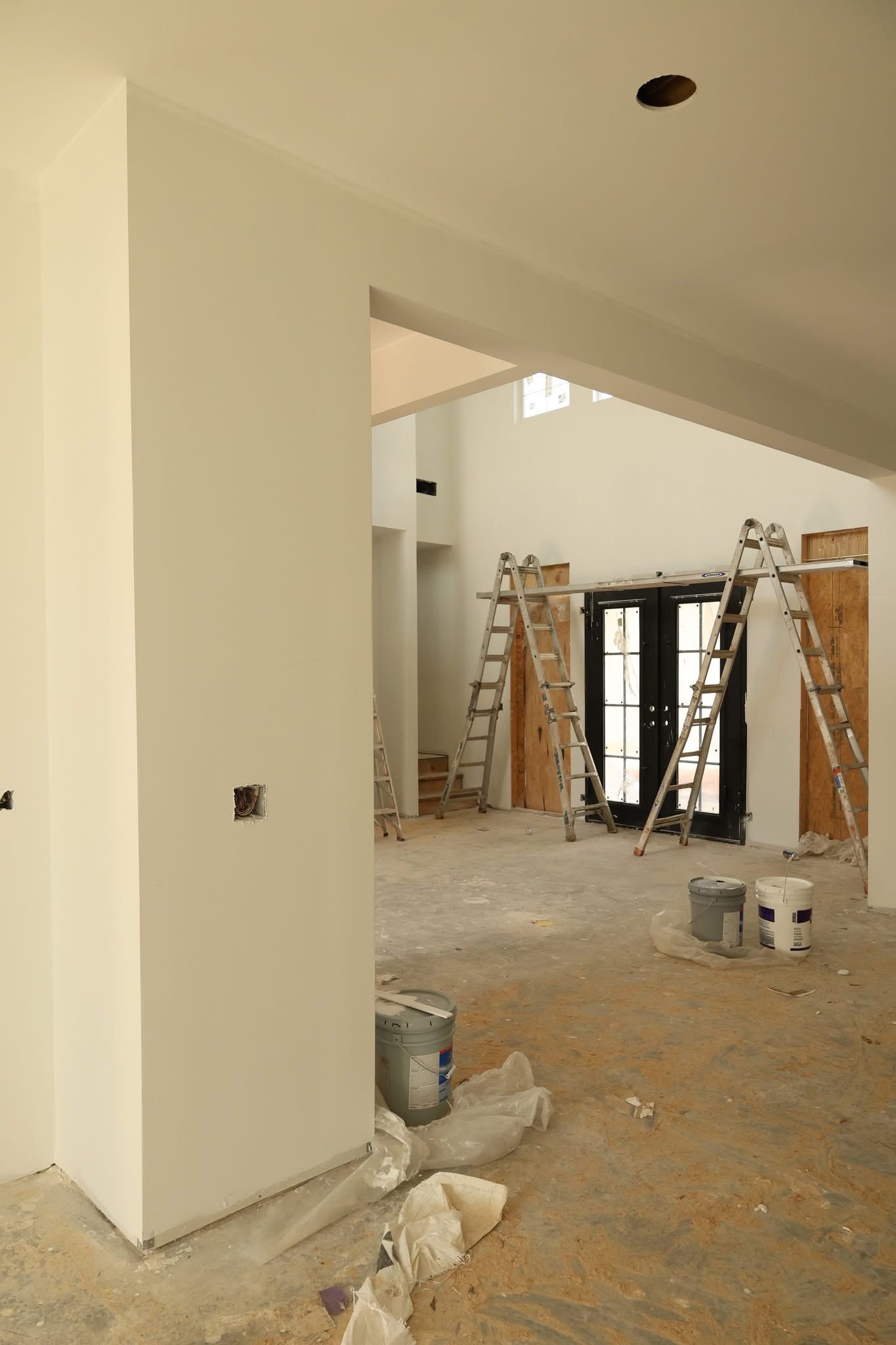 Modern farmhouse exterior nearing completion with white siding and black windows